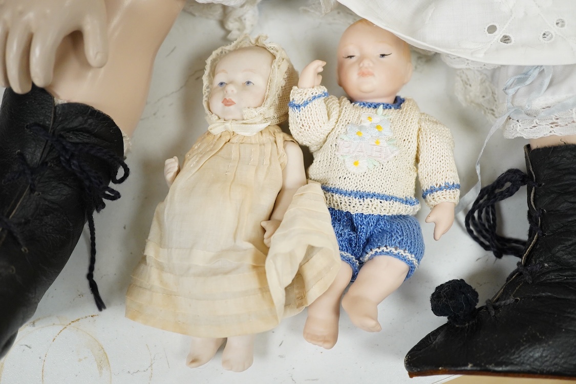 A large jointed bisque head doll and two miniature bisque dolls